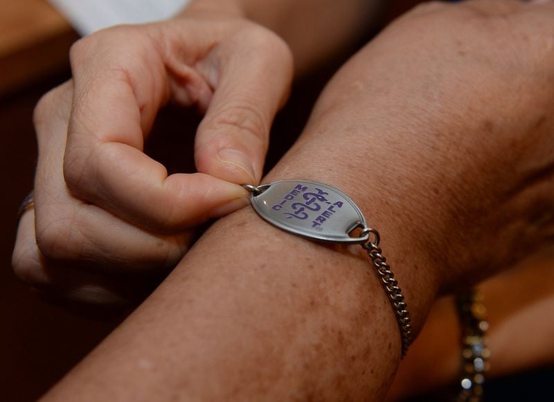In this file photo, a woman with the Alzheimer’s Association, places a medic alert bracelet on the arm of woman in the early stages of Alzheimer’s.