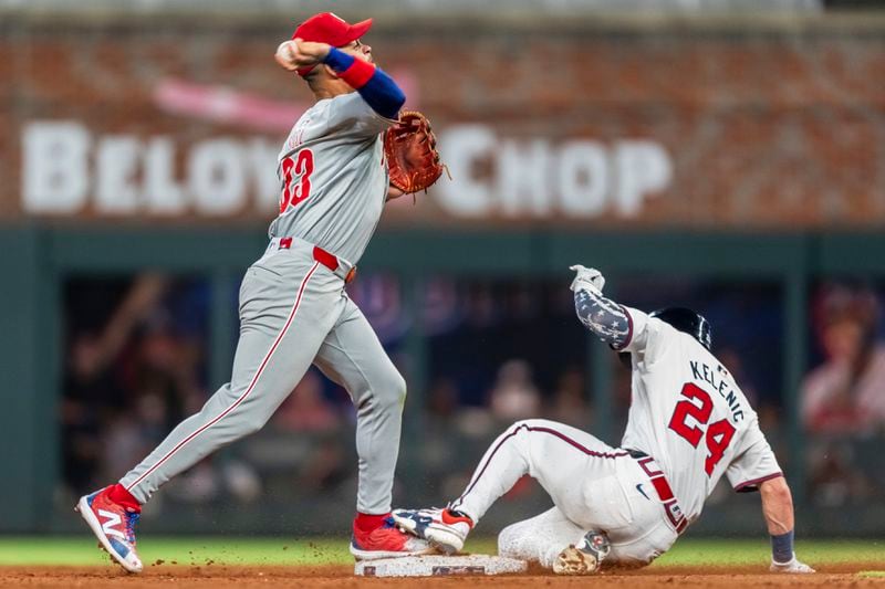 Philadelphia Phillies shortstop Edmundo Sosa, left, throws to first to turn the double play as Atlanta Braves' Jarred Kelenic (24) slides into second base to turn a double play in the seventh inning of a baseball game, Wednesday, Aug. 21, 2024, in Atlanta. (AP Photo/Jason Allen)