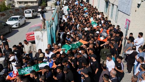 Mourners carry the bodies of 18 Palestinians who were killed in an Israeli airstrike during their funeral in Tulkarem, Friday, Oct. 4, 2024. (AP Photo/Nasser Nasser)