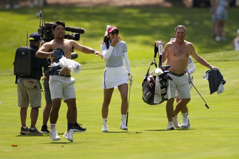 United States' Alison Lee, center, reacts flanked by celebrating caddies after finding the cup from the fairway on the second hole during a Solheim Cup golf tournament fourball match at Robert Trent Jones Golf Club, Saturday, Sept. 14, 2024, in Gainesville, Va. (AP Photo/Matt York)