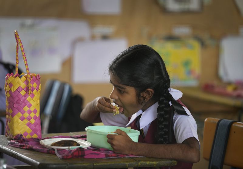 A primary student eats a free meal given at the school in Dalukana village in Dimbulagala north east of Colombo, Sri Lanka, Monday, Dec. 12, 2022. (AP Photo/Eranga Jayawardena, File)