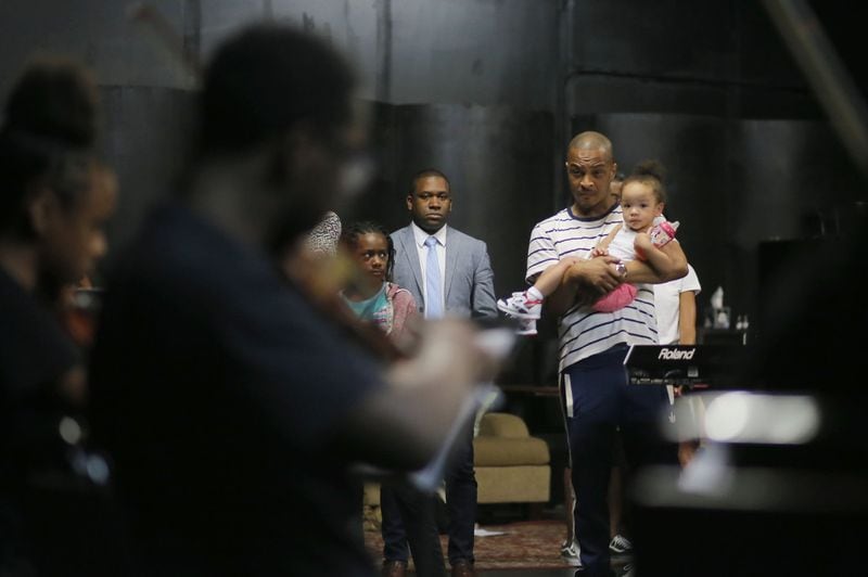 T.I., holding his daughter, watches students from the Atlanta Music Project run through their parts ahead of a July 12 NPR Music live concert. BOB ANDRES / BANDRES@AJC.COM