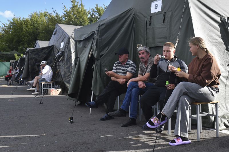 People evacuated from a fighting between Russian and Ukrainian forces in Kursk region sit next to tents at a temporary residence center in Kursk, Russia, Monday, Aug. 12, 2024. (AP Photo)