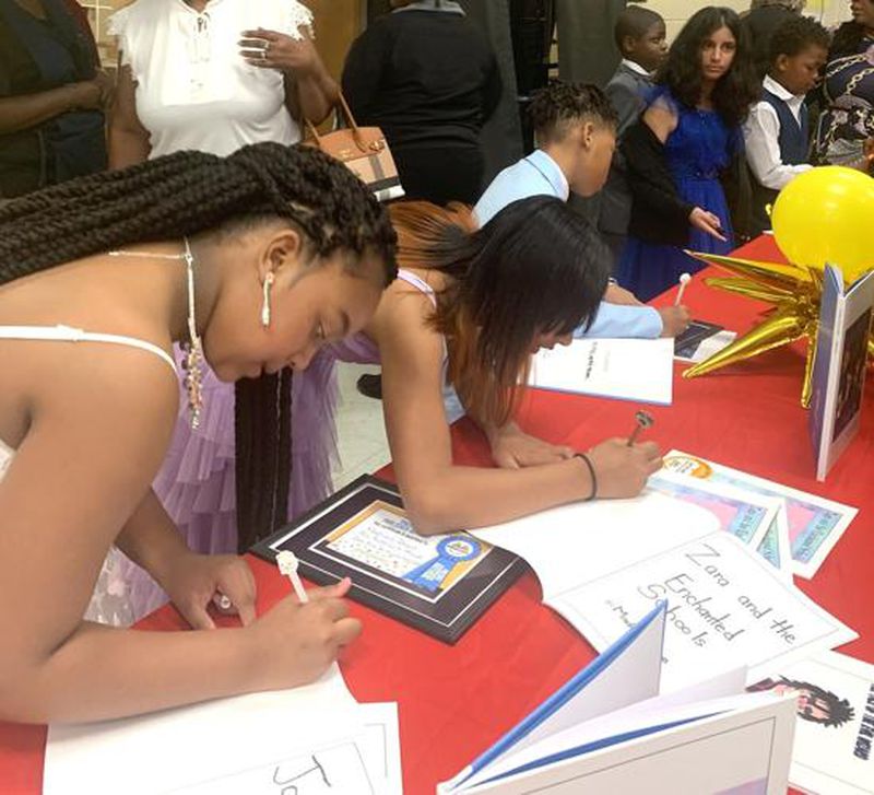 Students autograph copies of their books following this month's young authors program. (Photo provided by Alice Queen)