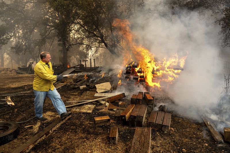 Shane Lawson, an off-duty firefighter, works to extinguish flames from the Grubbs Fire in the Palermo community of Butte County, Calif., on Wednesday, July 3, 2024. Firefighters stopped the fire at around 10 acres. An extended heatwave blanketing Northern California has resulted in red flag fire warnings and power shutoffs. (AP Photo/Noah Berger)