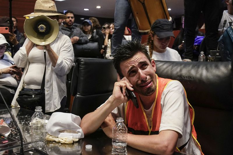 An injured protestor speaks on the phone after breaking into a Senate session in which lawmakers were debating the government's proposed judicial reform, which would make judges stand for election, in Mexico City, Tuesday, Sept. 10, 2024. (AP Photo/Felix Marquez)