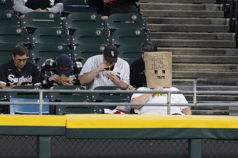 Christian Landreth, right from Glen Ellyn Illinois wears a bag on his head during a baseball game between the Chicago White Sox and the Los Angeles Angels during the first inning. The White Sox are going for the MLB record for loses122 if they lose tonight, Wednesday, Sept. 25, 2024, in Chicago. (AP Photo/David Banks)