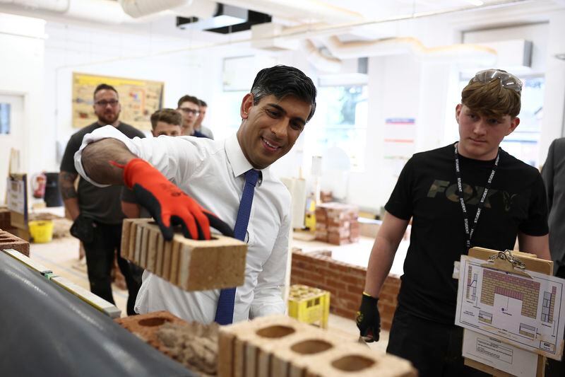 Britain's Prime Minister and Conservative Party leader Rishi Sunak, left, visits a bricklaying workshop at Cannock College, in Cannock, central England, Friday May 24, 2024, during a campaign event in the build-up to the UK general election on July 4. (Henry Nicholls/Pool via AP)