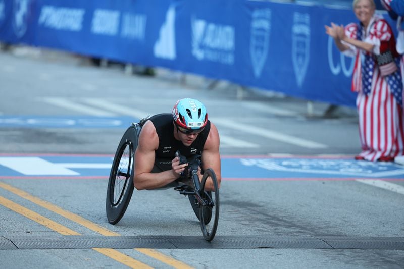 Daniel Romanchuk crosses the finish line to win the men’s wheelchair division of the 55th running of the Atlanta Journal-Constitution Peachtree Road Race in Atlanta on Thursday, July 4, 2024.   (Jason Getz / AJC)