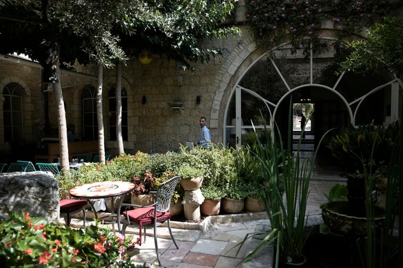 A worker walks through the garden courtyard where breakfast is served American Colony Hotel in east Jerusalem, Sunday, Aug. 18, 2024. As Israel’s economy is suffering from the nearly 11-month war with Hamas, Jerusalem’s iconic American Colony hotel has had to lay off workers and are mulling pay cuts, said Jeremy Berkovitz, the official representative of the owners. (AP Photo/Mahmoud Illean)