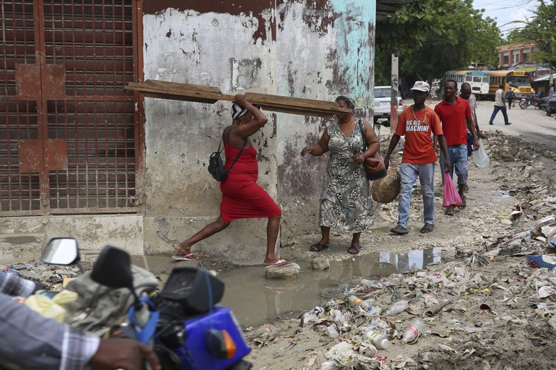 Pedestrians cross a puddle of water in downtown Port-au-Prince, Haiti, Monday, Sept. 23, 2024. (AP Photo/Odelyn Joseph)