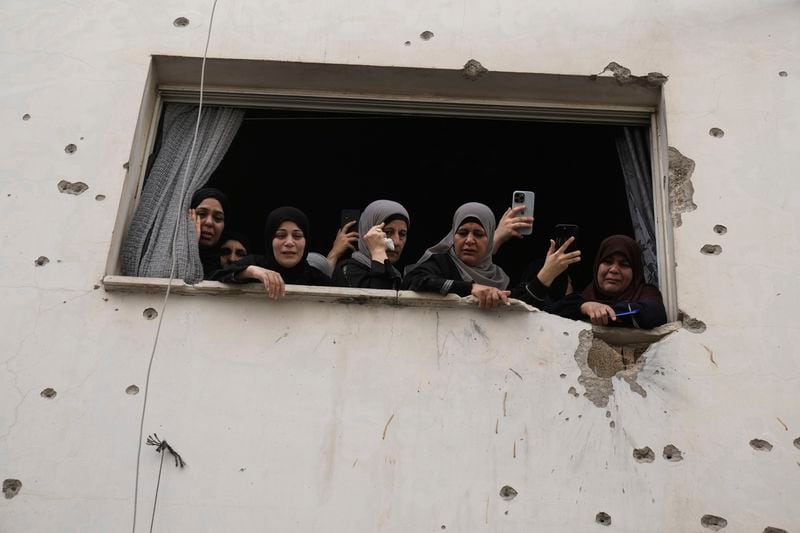 Mourners watch the funeral of Palestinian men who were killed during an Israeli military operation, from a building damaged with bullet holes, in Jenin, West Bank, Friday, Sept. 6, 2024. (AP Photo/Majdi Mohammed)