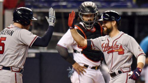 Miami Marlins' catcher Jorge Alfaro looks on as Braves' Ender Inciarte (right) is congratulated by teammate Freddie Freeman after hitting a home run during the sixth inning Sunday, June 13, 2021, in Miami. (Jim Rassol/AP)