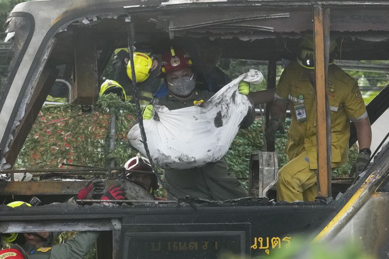 Rescuers carry the body of a victim of a bus that caught fire, carrying young students with their teachers, in suburban Bangkok, Tuesday, Oct. 1, 2024. (AP Photo/Sakchai Lalit)