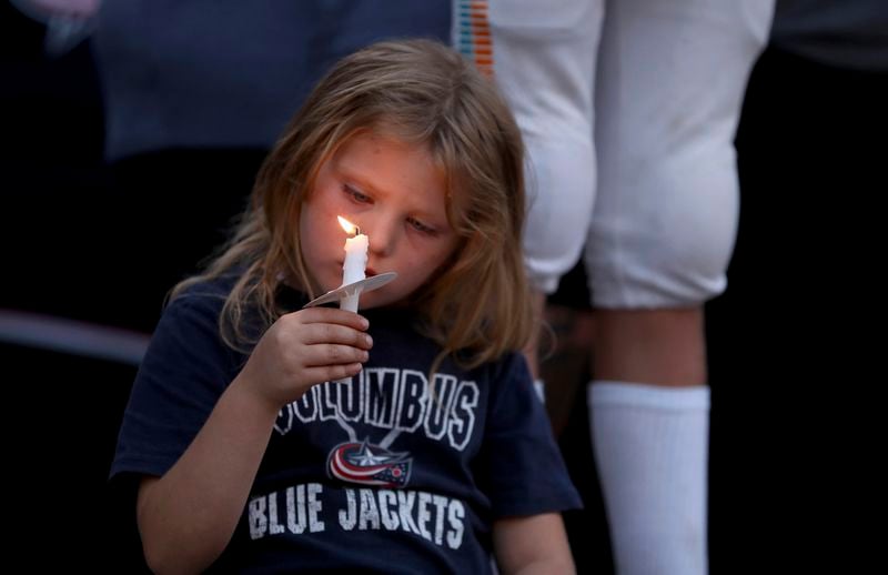 Columbus Blue Jackets fan Scarlett Well, has a moment of silence during the candlelight vigil to honor of Blue Jackets hockey player Johnny Gaudreau, outside of Nationwide Arena in Columbus, Ohio, Thursday, Sept. 4, 2024. Gaudreau and his brother Matthew were killed by a motor vehicle last week while riding bicycles. (AP Photo/Joe Maiorana)