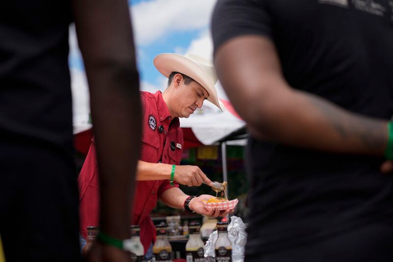 Alejandro Gutierrez of the Sociedad Mexicano de Parrillieros team prepares food for people to taste at the World Championship Barbecue Cooking Contest, Friday, May 17, 2024, in Memphis, Tenn. (AP Photo/George Walker IV)
