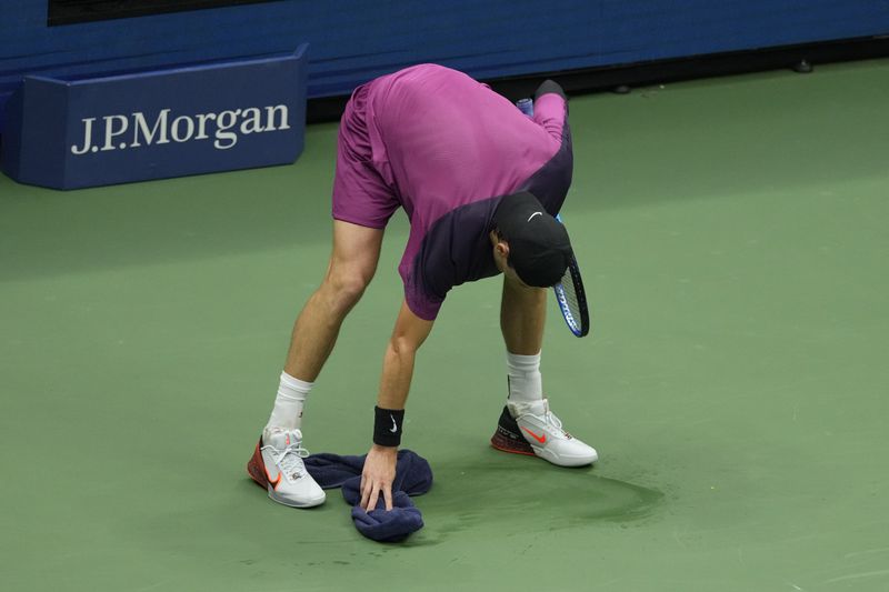 Jack Draper, of Great Britain, wipes the court against Jannik Sinner, of Italy, during the men's singles semifinals of the U.S. Open tennis championships, Friday, Sept. 6, 2024, in New York. (AP Photo/Seth Wenig)