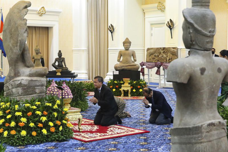 In this photo released by Agence Kampuchea Press (AKP), Cambodian Prime Minister Hun Manet, center, prays before a Buddha statue during a ceremony for the return of artifacts at Peace Palace in Phnom Penh, Cambodia, Thursday, Aug. 22, 2024. (AKP via AP)