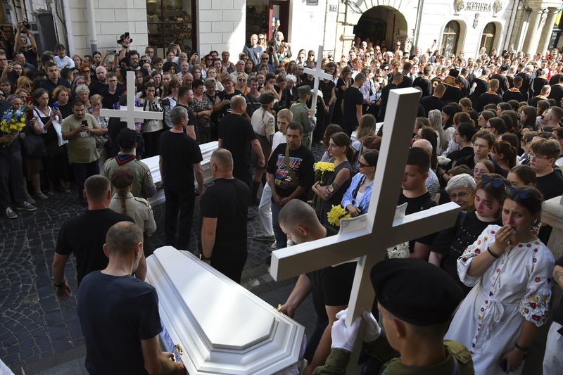 People carry the coffins of the family members of Yaroslav Bazylevych during the funeral procession in Lviv, Ukraine, Friday, Sept. 6, 2024. Bazylevych's wife Yevgenia and their three daughters - Darina, 18, Emilia, 7, and Yaryna, 21 - were killed in Wednesday's Russian missile attack. (AP Photo/Mykola Tys)