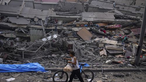 FILE - A Palestinian child walks with a bicycle by the rubble of a building after it was hit by an Israeli airstrike, in Gaza City, Oct. 8, 2023. (AP Photo/Fatima Shbair, File)