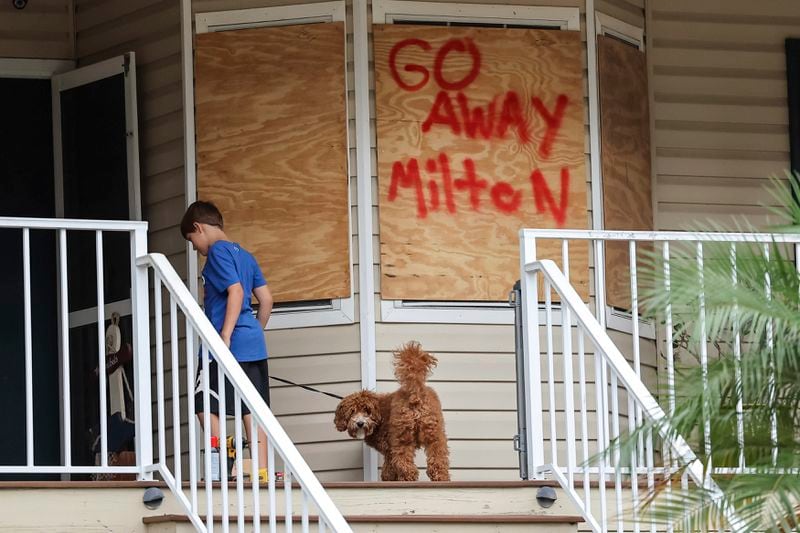 Noah Weibel and his dog Cookie climb the steps to their home as their family prepares for Hurricane Milton on Monday, Oct. 7, 2024, in Port Richey, Fla. (AP Photo/Mike Carlson)