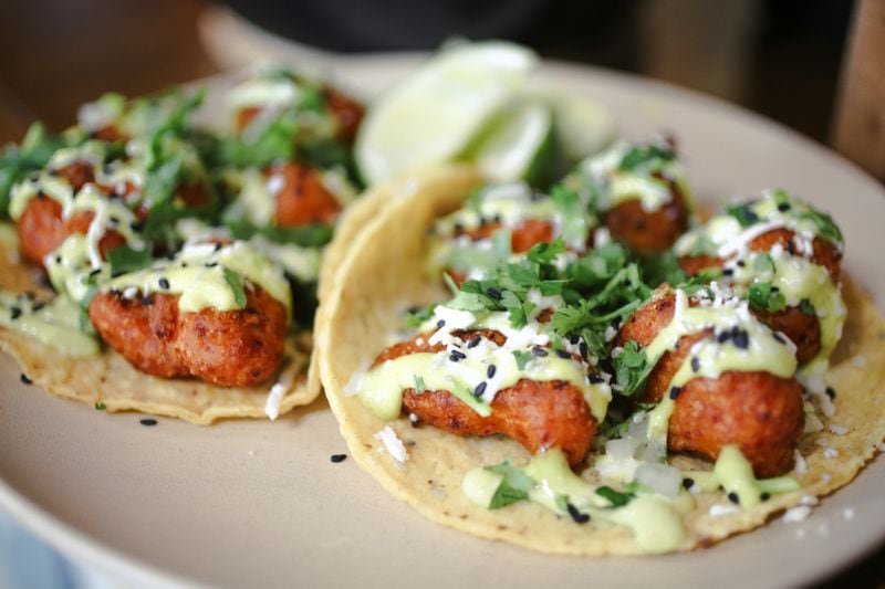 Bull Street Tacos' cauliflower tacos are served on a flour tortilla, with a smear of sauce, shredded lettuce and a sprinkling of cheese. (Adriana Iris Boatwright for The Atlanta Journal-Constitution) 