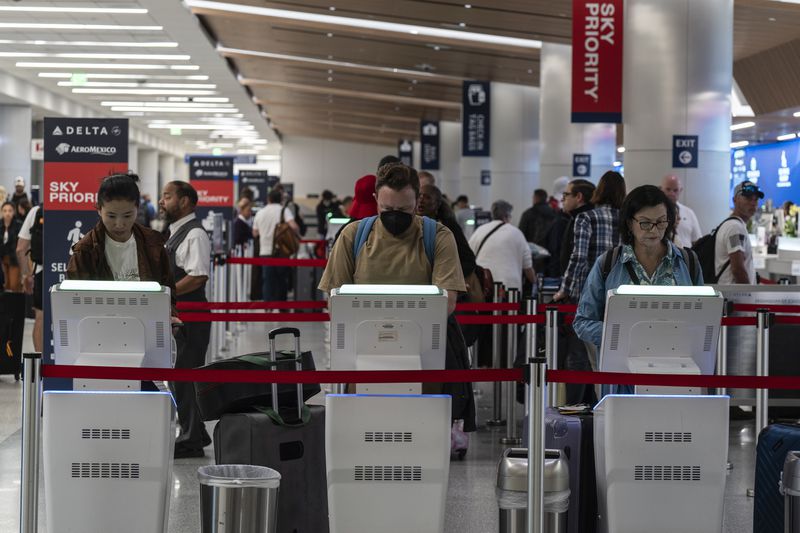 Travelers use kiosks to check in for flights in the Delta Airlines ticketing area at the Los Angeles International Airport in Los Angeles, Friday, Aug. 30, 2024. (AP Photo/Jae C. Hong)