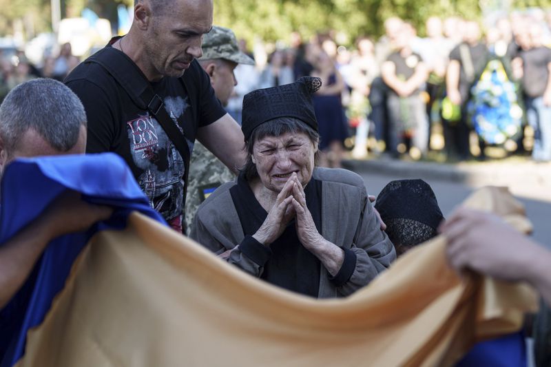 A mother cries near the coffin of her son killed by a Russian rocket attack at a Ukrainian military academy, during his funeral ceremony in Poltava, Ukraine, Saturday Sept. 7, 2024. (AP Photo/Evgeniy Maloletka)