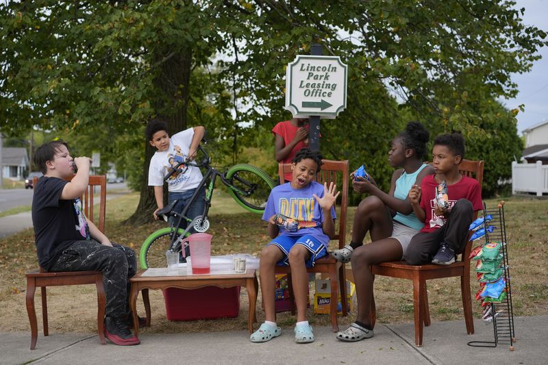 Neighborhood kids gather to sell Kool-Aid and chips, Tuesday, Sept. 17, 2024, in Springfield, Ohio. Some were kept home from school because of the bomb threats at their schools, and if that happens again, they plan to be at the corner with Kool-Aid and chips again tomorrow. (AP Photo/Carolyn Kaster)