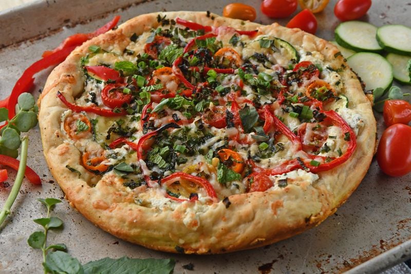 Farmers Market Pizza is topped with items such as zucchini and halved cherry tomatoes. (Styling by Susan Puckett / Chris Hunt for the AJC)