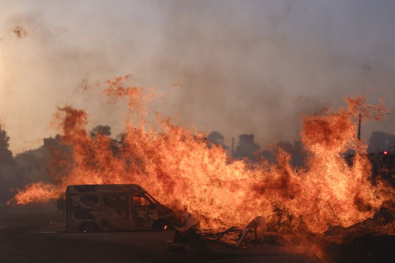 The fire burns a vehicle during a fire in northern Athens, Monday, Aug. 12, 2024, as hundreds of firefighters tackle a major wildfire raging out of control on fringes of Greek capital. (AP Photo/Aggelos Barai)