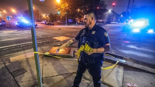 An Atlanta police officer collects crime scene tape at the corner of Fulton and Pryor streets after wrapping up a shooting investigation Tuesday morning. A woman was killed when her Cadillac SUV took gunfire, according to police.