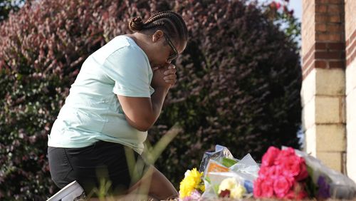 Linda Carter, of Grayson, Ga., kneels near Apalachee High School to place flowers as she mourns for the slain students and teachers on Thursday, Sept. 5, 2024, in Winder, Ga. (AP Photo/Brynn Anderson)