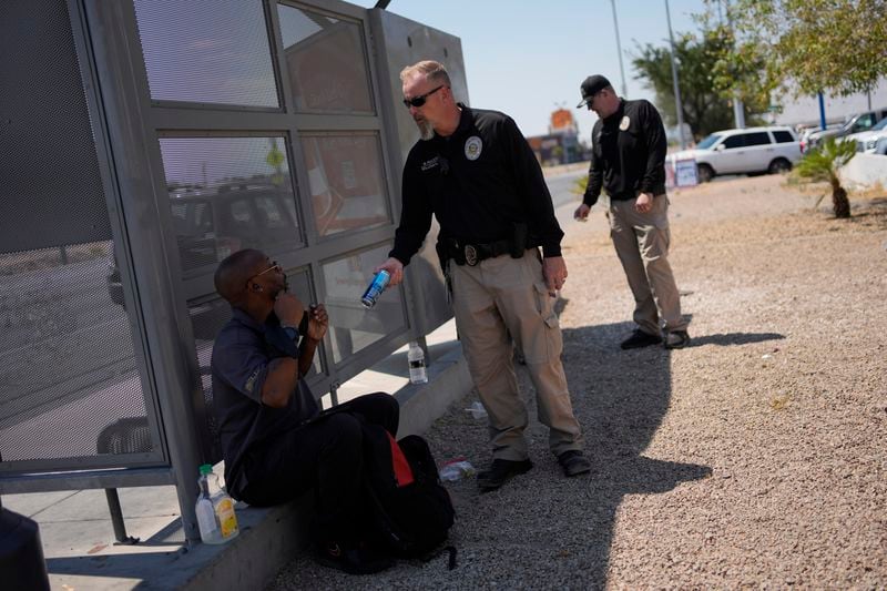 Mark Paulson, a Public Response and Code Enforcement officer, hands out cold water, Wednesday, July 10, 2024, during a heat emergency in Henderson, Nev. (AP Photo/John Locher)
