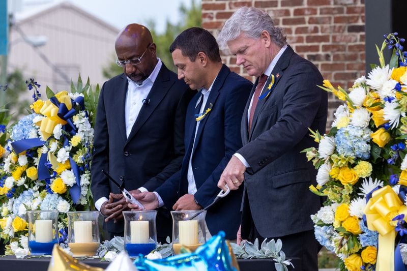 (L-R) U.S. Sen. Raphael Warnock, D-Ga., Barrow County Superintendent Dallas LeDuff, and U.S. Rep. Mike Collins, R-Jackson, light candles at a vigil at Jug Tavern Park in Winder on Friday, Sept. 6, 2024. A 14-year-old Apalachee High School student is accused of shooting and killing two fellow students and two teachers and injuring nine others at the high school on Wednesday.