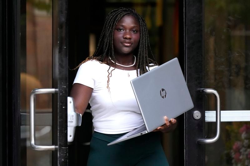 Adjovi Golo holds a laptop as she walks out from a dormitory at DePaul University in Chicago, Wednesday, Aug. 28, 2024. (AP Photo/Nam Y. Huh)