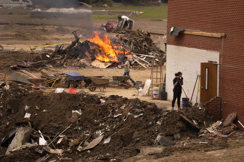 People clean up debris left in the aftermath of Hurricane Helene Friday, Oct. 4, 2024, in Erwin, Tenn. (AP Photo/Jeff Roberson)