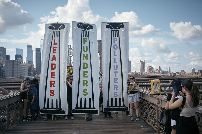 Protesters carry placards as they cross the Brooklyn Bridge during a Youth Climate Strike march to demand an end to the era of fossil fuels, Friday, Sept. 20, 2024, in New York. (AP Photo/Andres Kudacki)