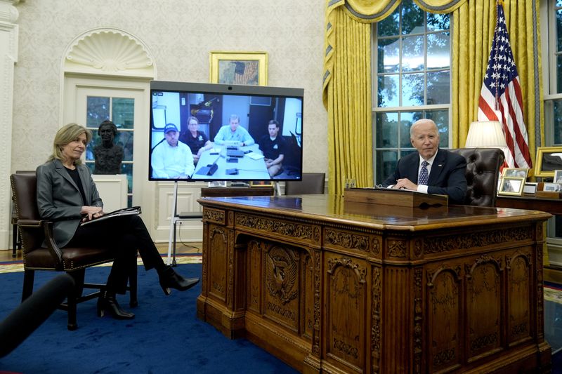 President Joe Biden, right, and White House Homeland Security Advisor Liz Sherwood-Randall, left, speak with North Carolina Gov. Roy Cooper, on screen at center right, and Administrator of the U.S. Federal Emergency Management Agency Deanne Criswell, onscreen at center left, about the Biden administration's efforts to aid in recovery from the aftermath of Hurricane Helene from the Oval Office of the White House in Washington, Monday, Sept. 30, 2024. (AP Photo/Mark Schiefelbein)