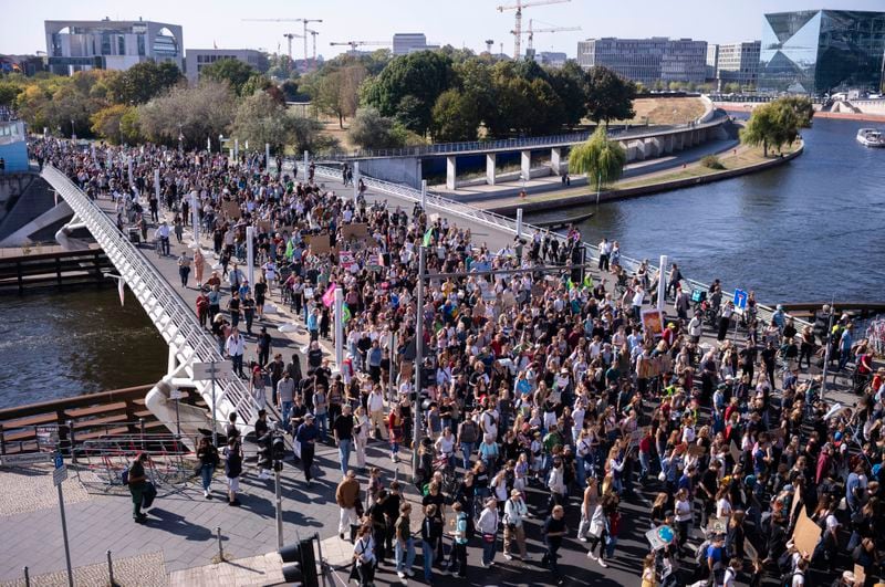 Demonstrators of the Fridays For Future movement march through the government district near the chancellery, background left, as they take part in a Global Climate Strike in Berlin, Germany, Friday, Sept. 20, 2024. (AP Photo/Markus Schreiber)