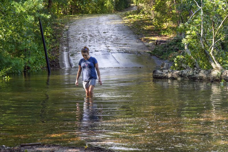 FILE - Teresa Elder walks through a flooded Sandy Cove Drive from Hurricane Helene on Sept. 27, 2024, in Morganton, N.C. (AP Photo/Kathy Kmonicek, File)