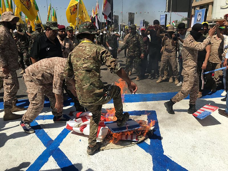 FILE - Popular Mobilization Forces burn representations of U.S. and Israeli flags during "al-Quds" Day, Arabic for Jerusalem, in Baghdad, Iraq, May 31, 2019. Thousands of fighters from Iran-backed groups in the Middle East are offering to come to Lebanon to join the militant Hezbollah group in its fight with Israel. (AP Photo/Ali Abdul Hassan, File)