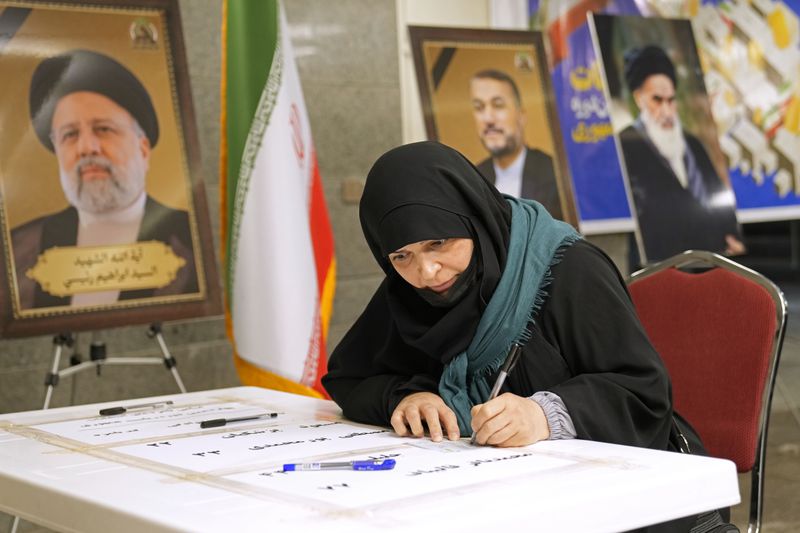 A woman casts her vote during the presidential election at a polling station inside the Iranian embassy in Baghdad, Iraq, Friday, June 28, 2024. (AP Photo/Hadi Mizban)