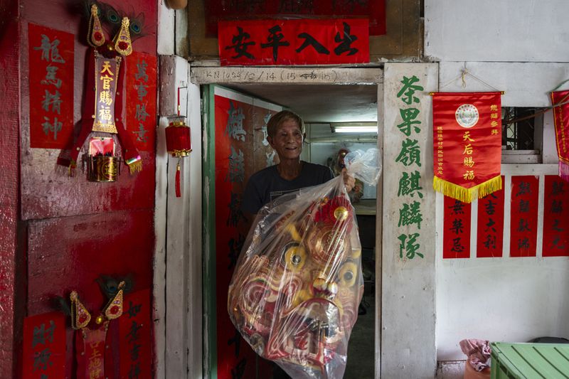 Villager Lo Yuet-ping carries the head prop that's used in the traditional "Qilin" Dance at the Cha Kwo Ling village in east Kowloon, Hong Kong, Sunday, Aug. 25, 2024. (AP Photo/Chan Long Hei)