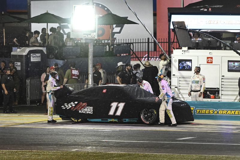 Thee pit crew for Denny Hamlin put a tarp over the car as rain falls during a NASCAR Cup Series auto race at Charlotte Motor Speedway, Sunday, May 26, 2024, in Concord, N.C. (AP Photo/Matt Kelley)
