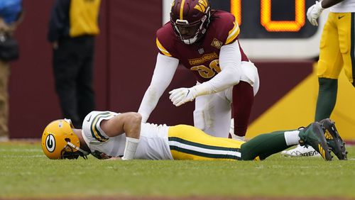 Green Bay Packers quarterback Aaron Rodgers (12) lays on the turf with Washington Commanders defensive end James Smith-Williams (96) over him after an NFL football game Sunday, Oct. 23, 2022, in Landover, Md. The Commanders won 23-21. (AP Photo/Patrick Semansky)