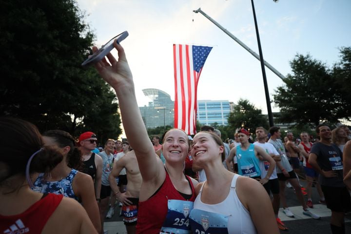 Runners take selfie at the start of the 55th running of the Atlanta Journal-Constitution Peachtree Road Race in Atlanta on Thursday, July 4, 2024.   (Miguel Martinez / AJC)