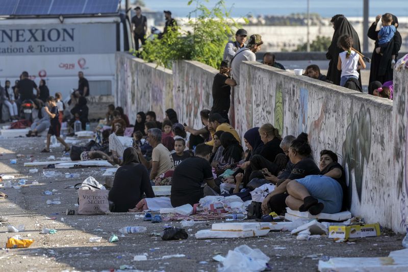 Families sit on the ground in Martyrs' square after fleeing the Israeli airstrikes in Beirut's southern suburbs, Saturday, Sept. 28, 2024. (AP Photo/Bilal Hussein)