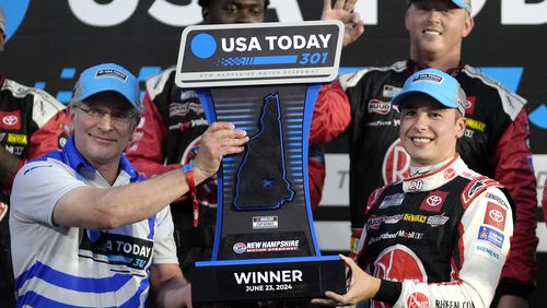 Howard Altschiller, left, executive editor of Seacoast Media Group, presents Christopher Bell, right, with the winner's trophy during ceremonies after Bell won the NASCAR Cup Series race, Sunday, June 23, 2024, at New Hampshire Motor Speedway in Loudon, N.H. (AP Photo/Steven Senne)