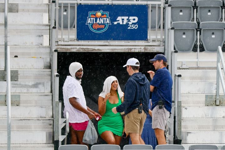 Tennis fans cover themselves from the rain as they speak to volunteers. The rain delayed the opening exhibition match at the Atlanta Open tennis tournament at Atlantic Station on Sunday, July 21, 2024.
(Miguel Martinez / AJC)